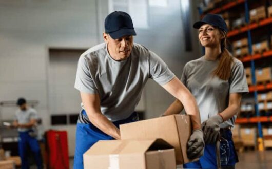 Un homme et une femme chargent des cartons dans un entrepôt