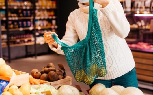 Un client achète des fruits et légumes dans une boutique avec un contenant réutilisable