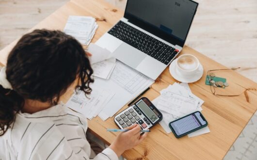 Une femme devant son ordinateur et sa calculatrice sur la gestion des immobilisations