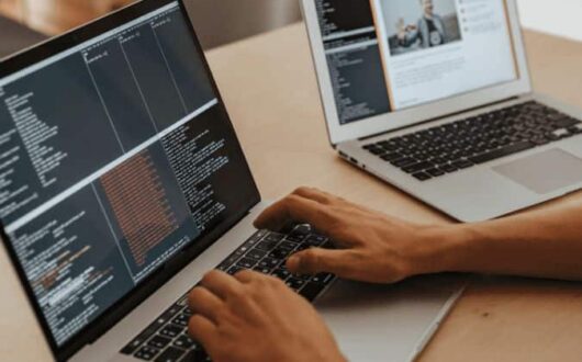 Une personne devant un ordinateur face à un écran de code