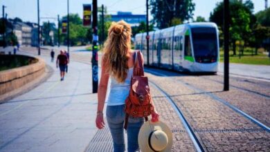 Femme marchant en pleine ville, face à un tramway dans une rue sans voiture