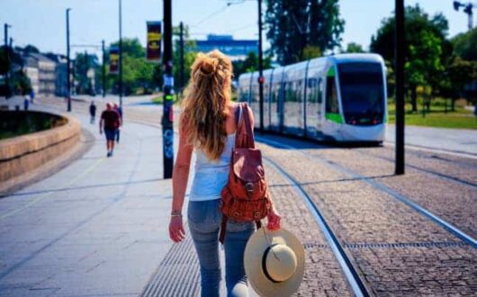 Femme marchant en pleine ville, face à un tramway dans une rue sans voiture