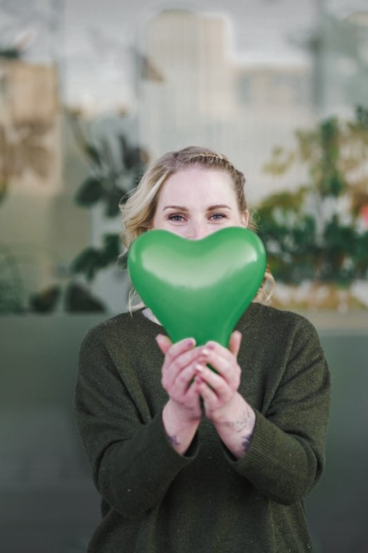 Femme tenant un cœur vert entre les mains, symbole de Green IT