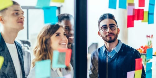 Des collaborateurs devant un mur de post-its