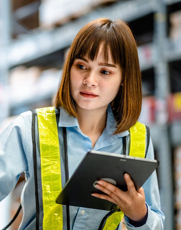 Une femme optimise sa gestion d'entrepôt avec les données de son WMS sur tablette