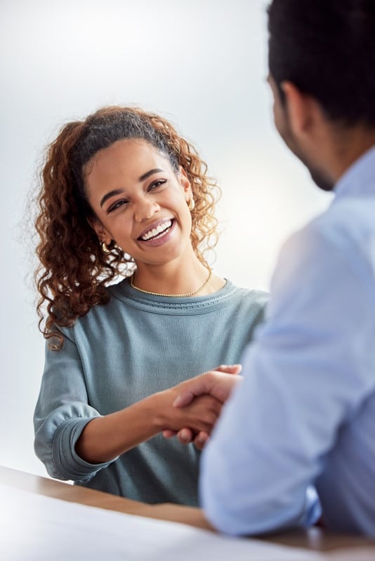 Une femme serre la main à un homme vu de dos