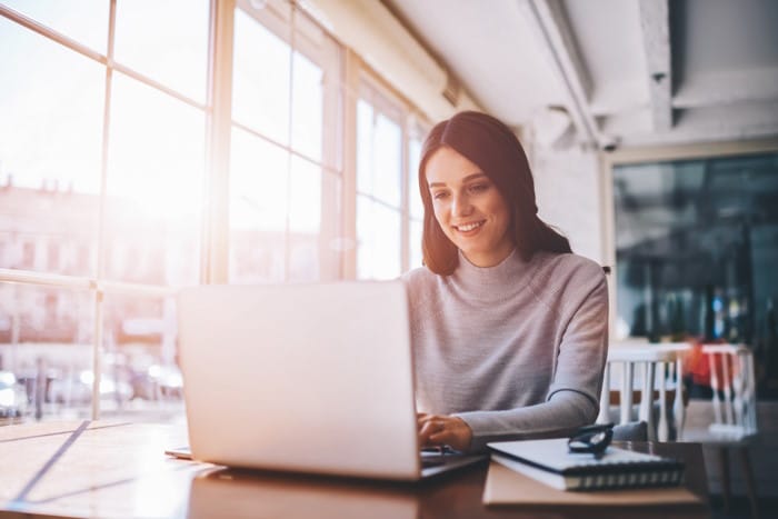 Une femme travaille sur son CRM depuis son ordinateur portable