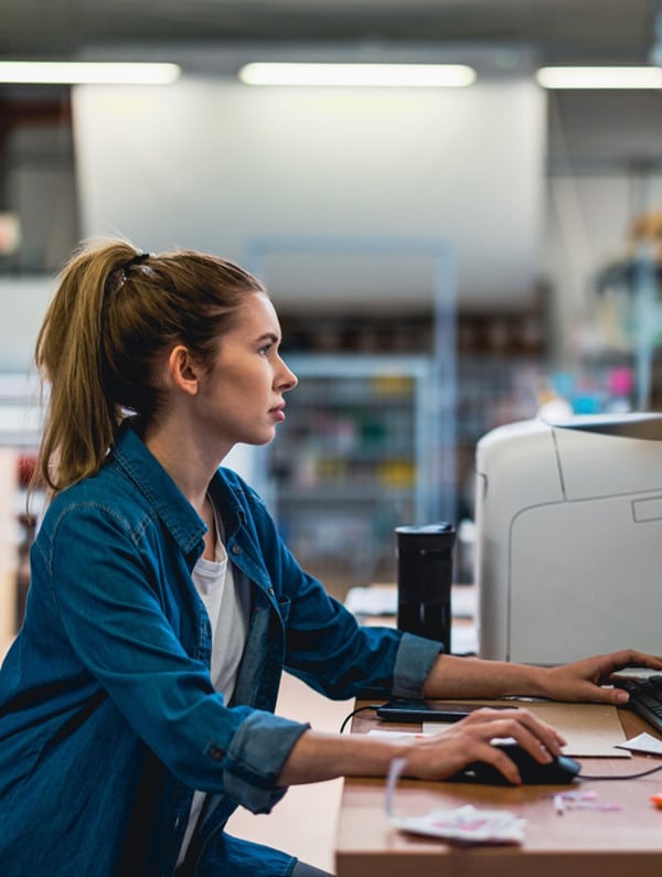 Sur ordinateur et dans un entrepôt, une femme gère son stockage avec le WMS